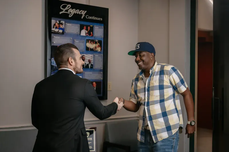 Chip Forstall shaking hands in front of the Legacy Continues wall