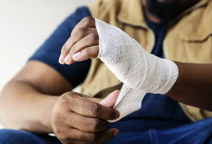 Una persona lesionada vendándose la muñeca